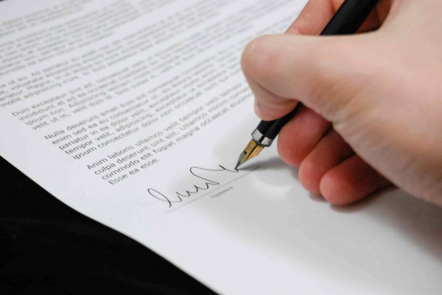 Close-up of a hand signing a legal document with a fountain pen