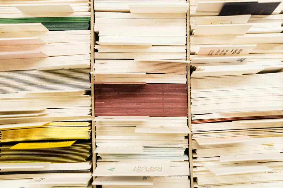 Stacks of color-coded paper documents organized in filing shelves representing document management system
