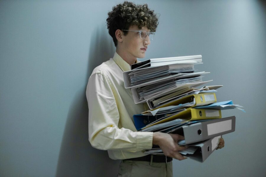 Professional carrying stack of government document binders representing PDF remediation backlog